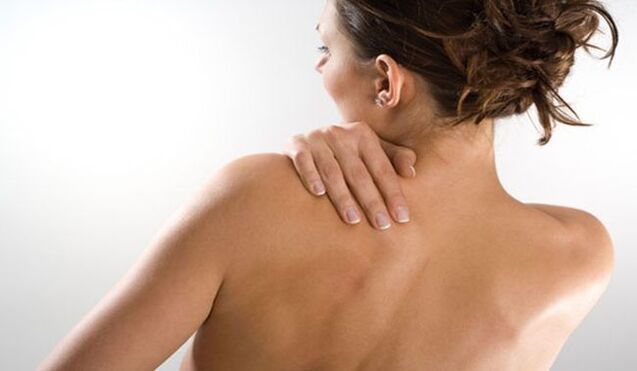 De vrouw maakt zich zorgen over de pijn onder het linkerschouderblad in de rug van achteren